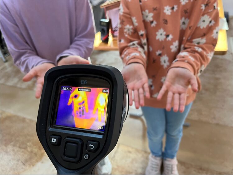 Kinder führen ein Experiment mit der Wärmebildkamera durch