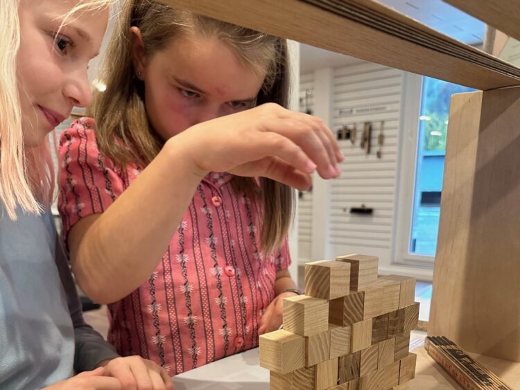 Mädchen erbauen einen Turm aus Holzwürfelchen