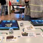 Spieltisch mit Spielbrett, Karten und Tablets